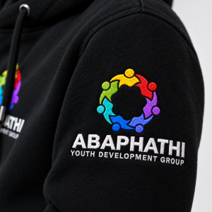 Close-up of embroidered ABAPATHI Youth Development Group branding on black hoodie